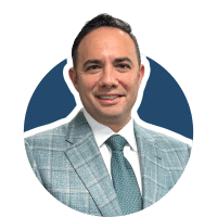 Portrait of a smiling man in a light blue plaid suit with tie against a blue circular background
