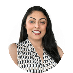 A person with dark hair smiling at the camera, wearing a sleeveless top with a black and white geometric pattern.
