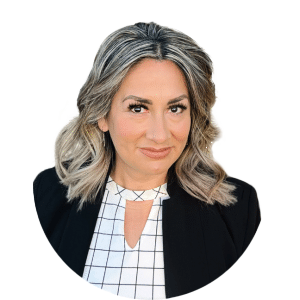 Portrait of a smiling woman with shoulder-length gray hair, wearing a black blazer and white checkered top