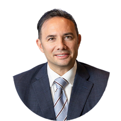 Headshot of a man in a dark suit and striped tie on a white background