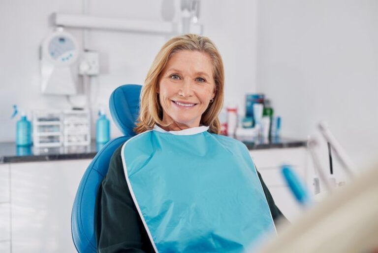 Smiling dentist in a blue bib seated in a dental clinic examination chair