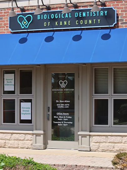 Biological Dentistry of Kane County storefront with blue awning and glass entrance under a brick facade
