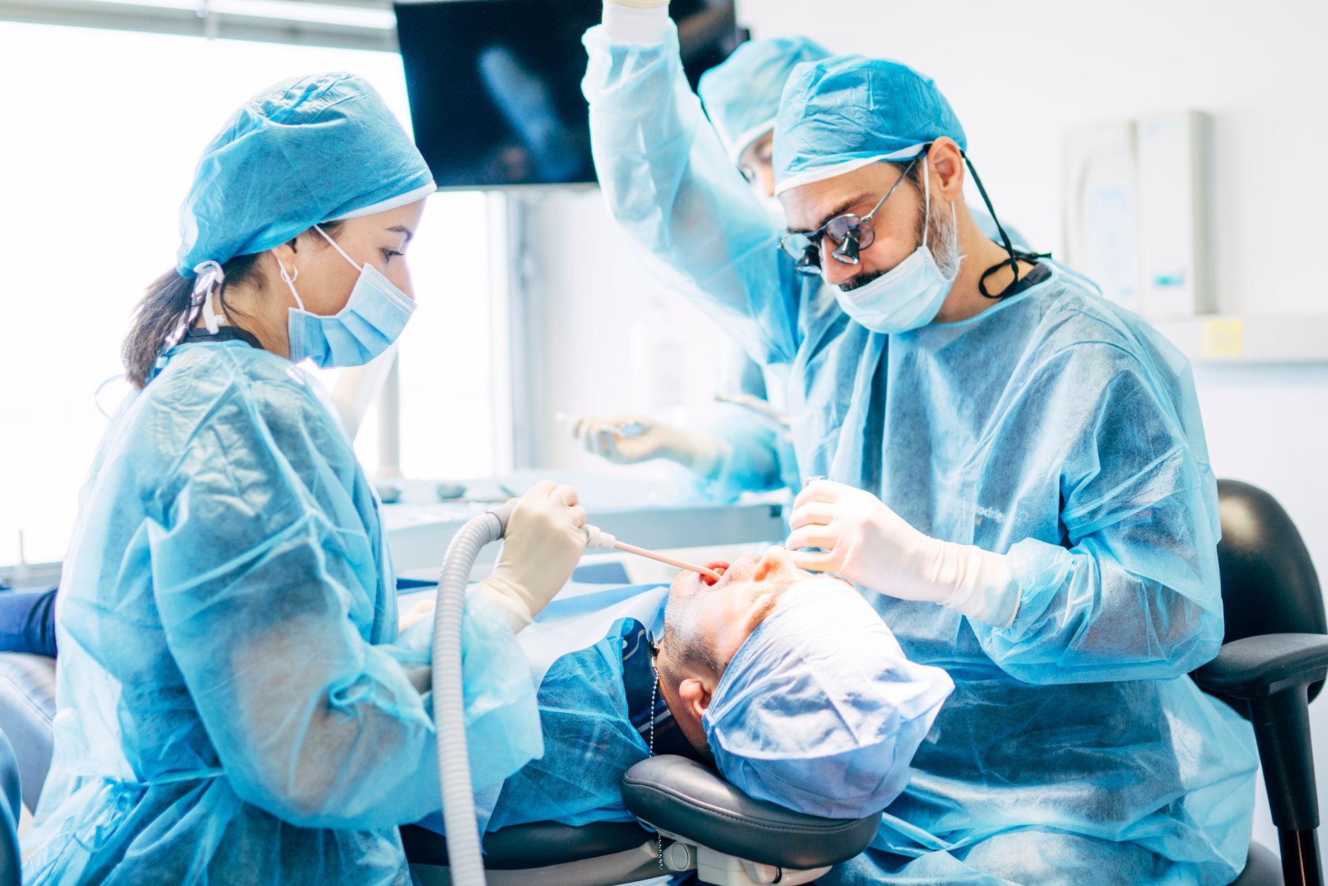 Two surgeons in blue scrubs operating in a bright hospital room