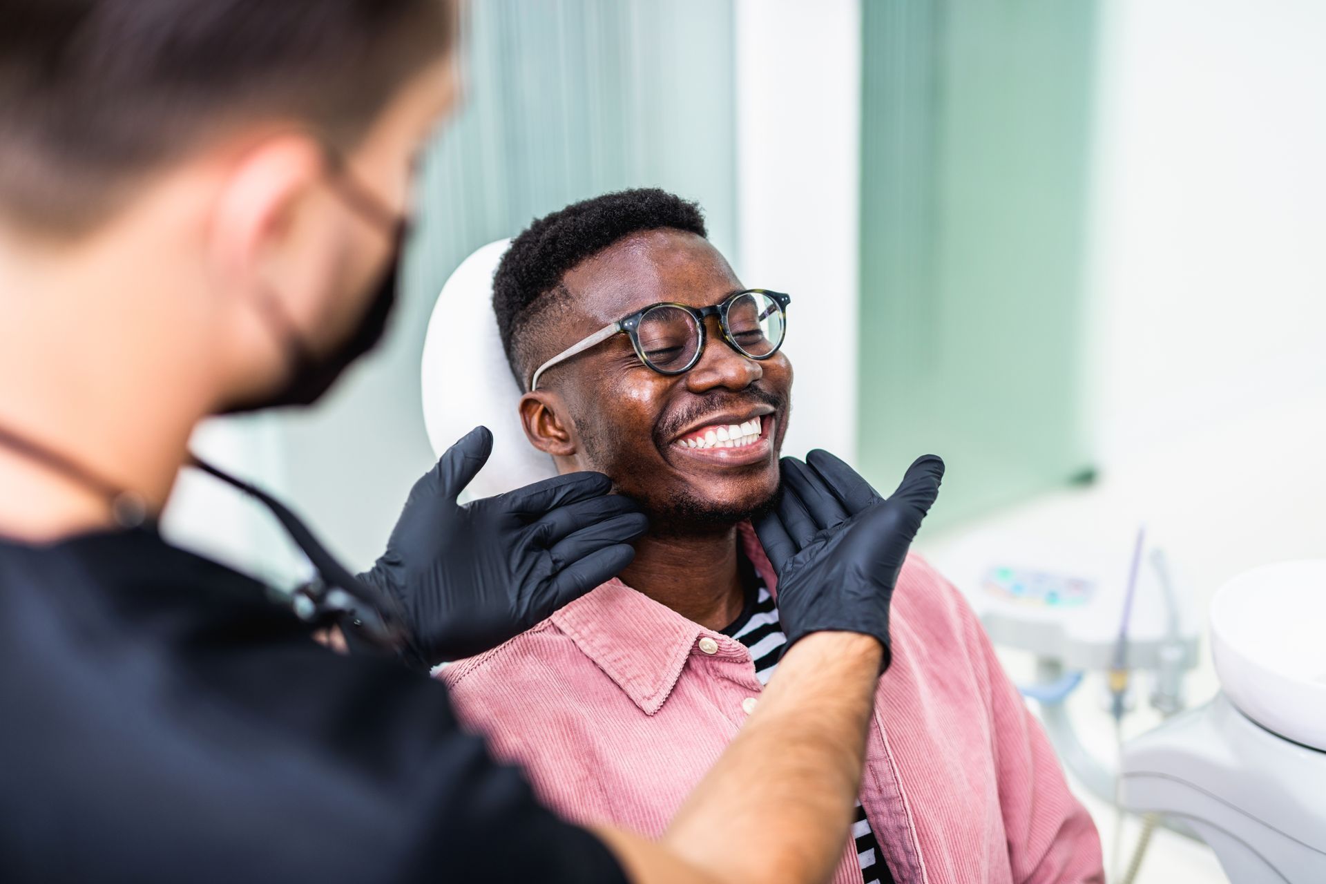 Dentist examining smiling patient’s mouth in a bright clinic