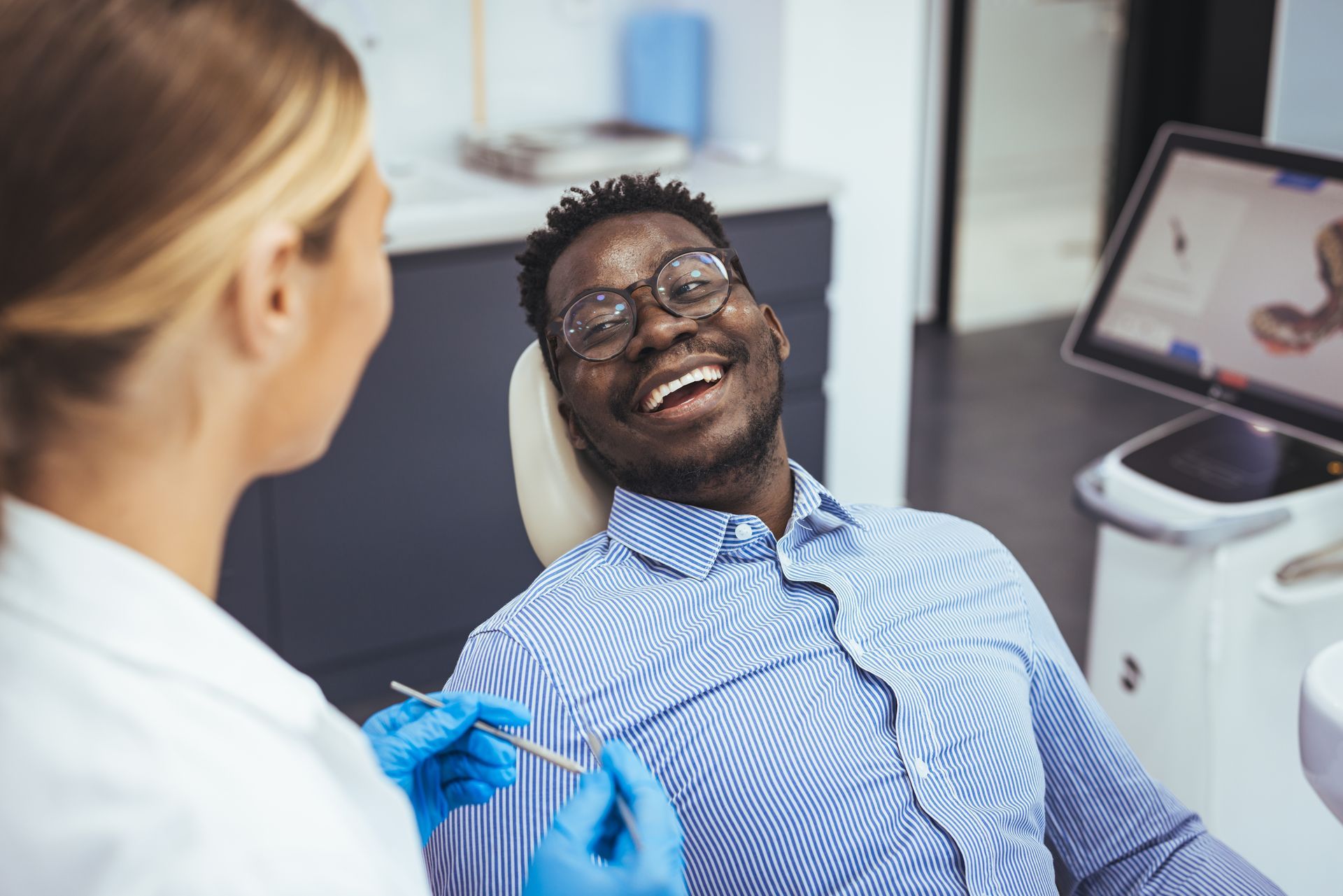 Dentist with blue gloves smiling at reclining patient in a dental clinic