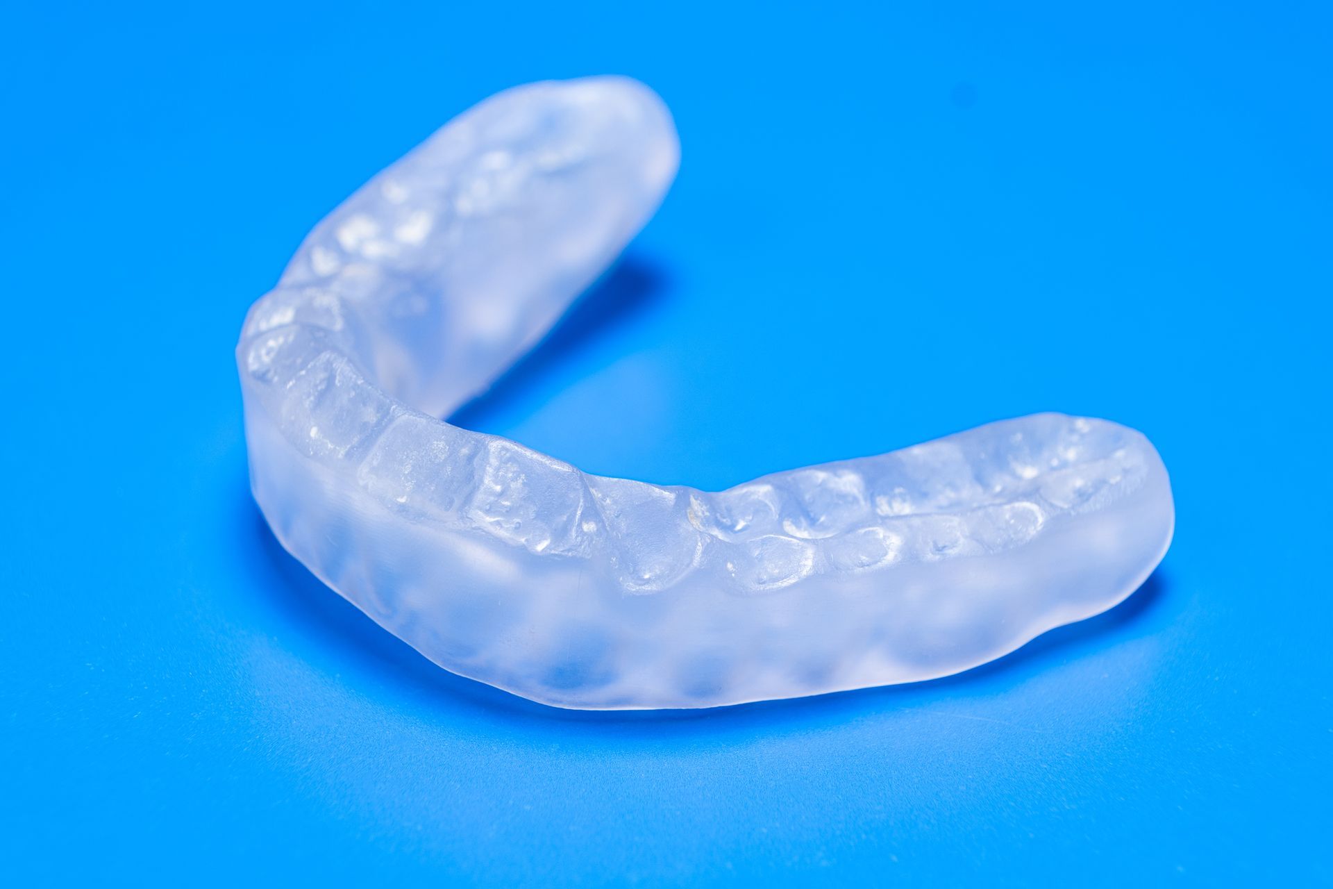 Transparent U-shaped dental mouthguard on a blue background