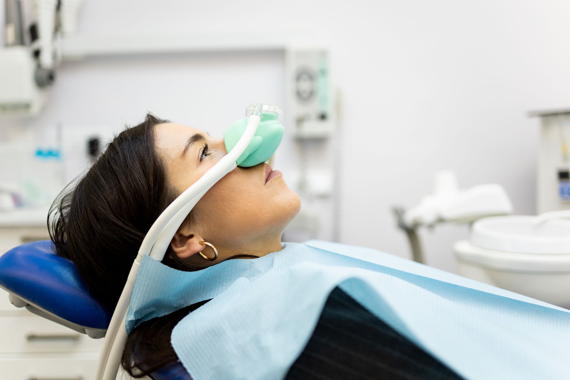 Patient reclining in a dental chair wearing an oxygen mask during a dental procedure