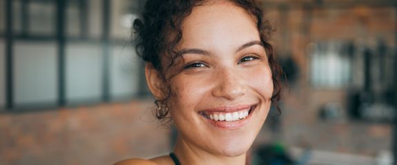Smiling person in a blurred indoor setting with warm lighting