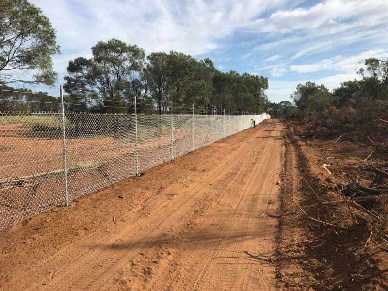 A Dirt Road With A Chain Link Fence On The Side Of It — Mulch, Fencing And Landscaping Mackay, QLD