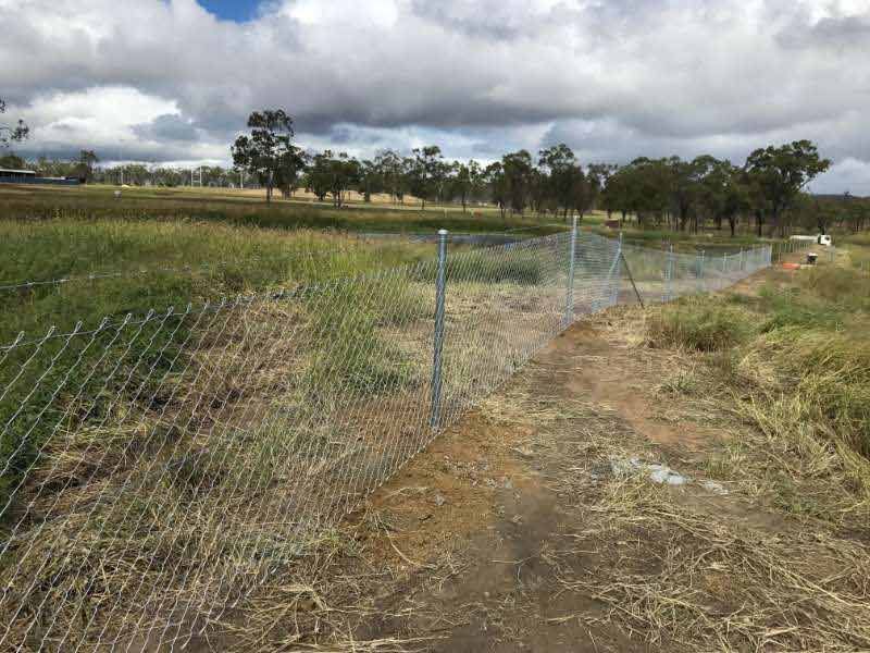 A Chain Link Fence Surrounds A Dirt Path In A Field — Mulch, Fencing And Landscaping Mackay, QLD
