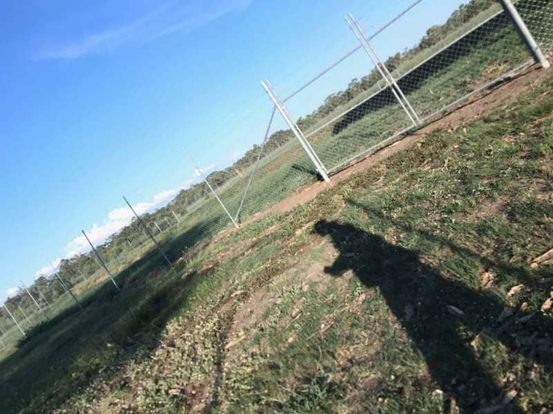 A Person 's Shadow Is Cast On The Ground In Front Of A Chain Link Fence — Mulch, Fencing And Landscaping Mackay, QLD