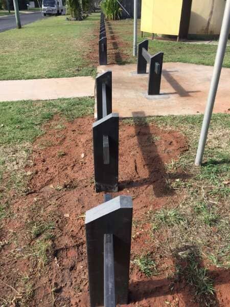 A Row Of Black Poles In The Dirt Next To A Sidewalk — Mulch, Fencing And Landscaping Mackay, QLD