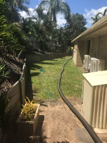 A Hose Is Connected To A House In A Backyard — Mulch, Fencing And Landscaping Mackay, QLD