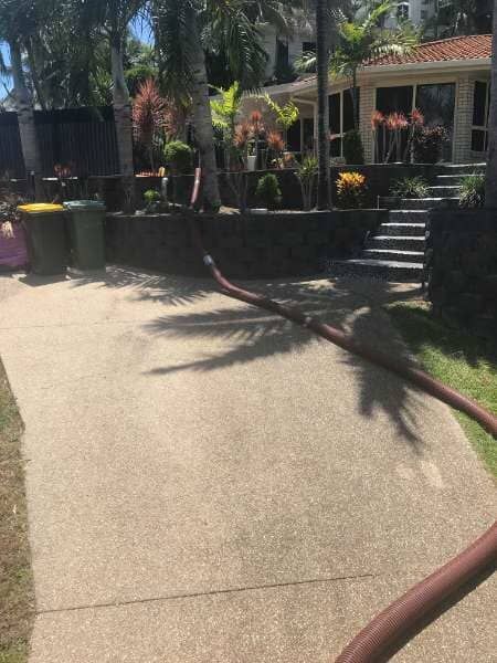 A Hose Is Laying On The Sidewalk In Front Of A House — Mulch, Fencing And Landscaping Mackay, QLD
