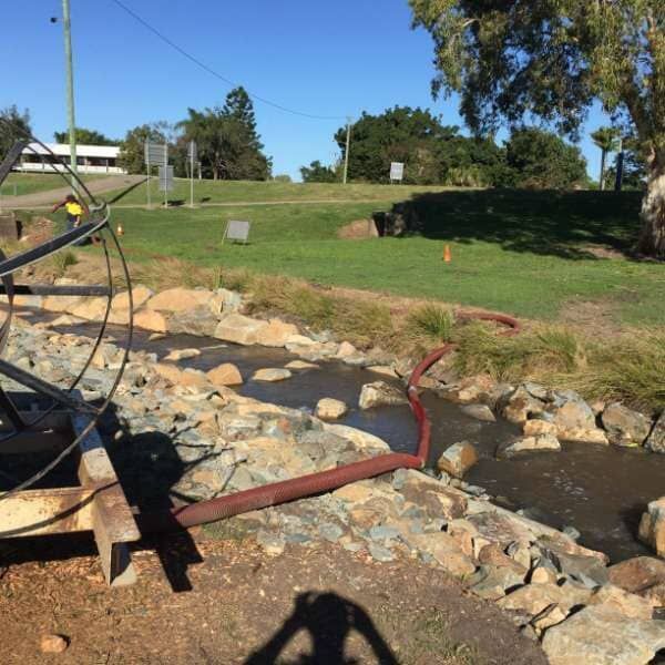 A Shadow Of A Person Is Cast On The Ground Near A Stream — Mulch, Fencing And Landscaping Mackay, QLD