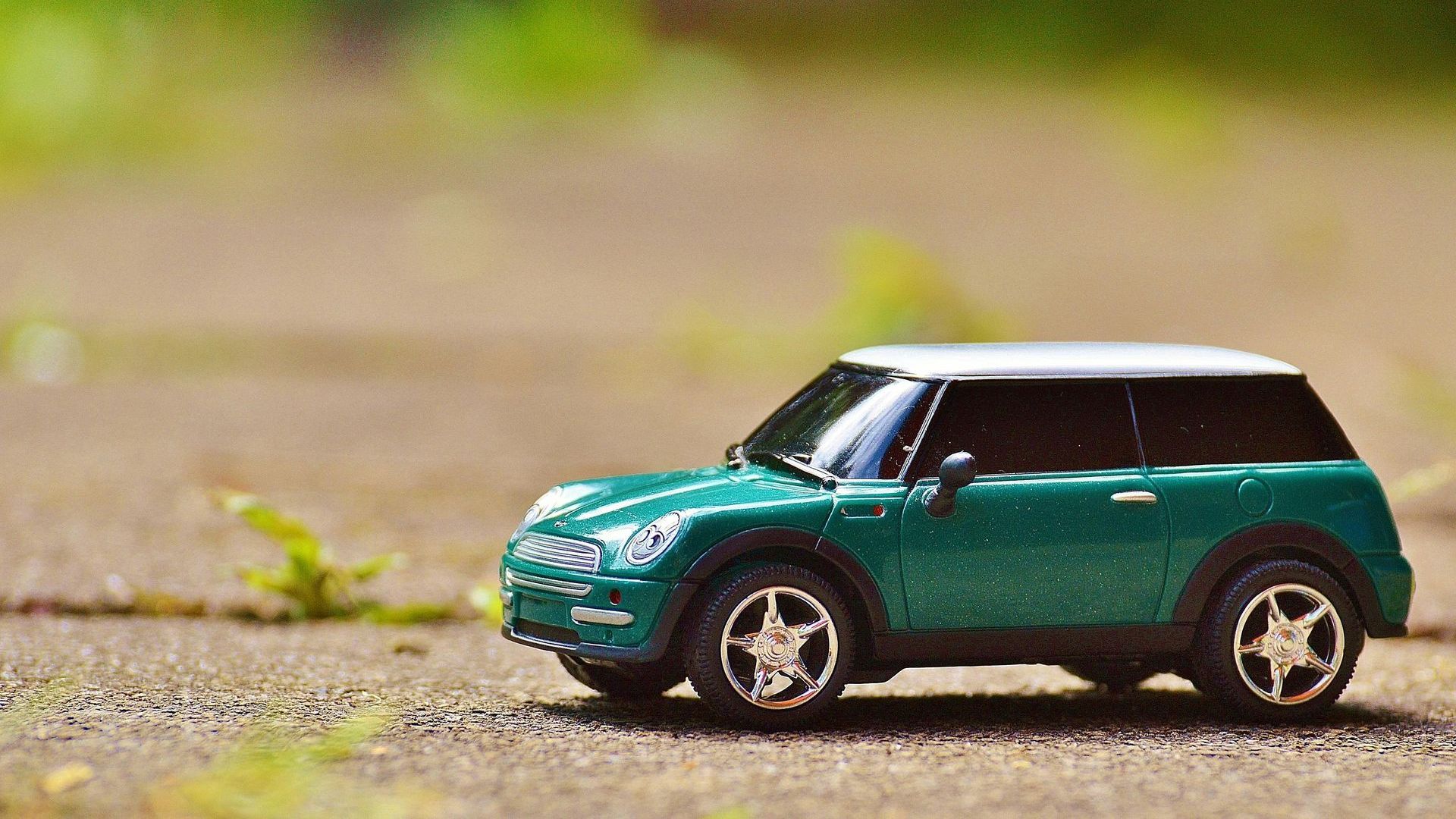 A green toy car is sitting on the ground.
