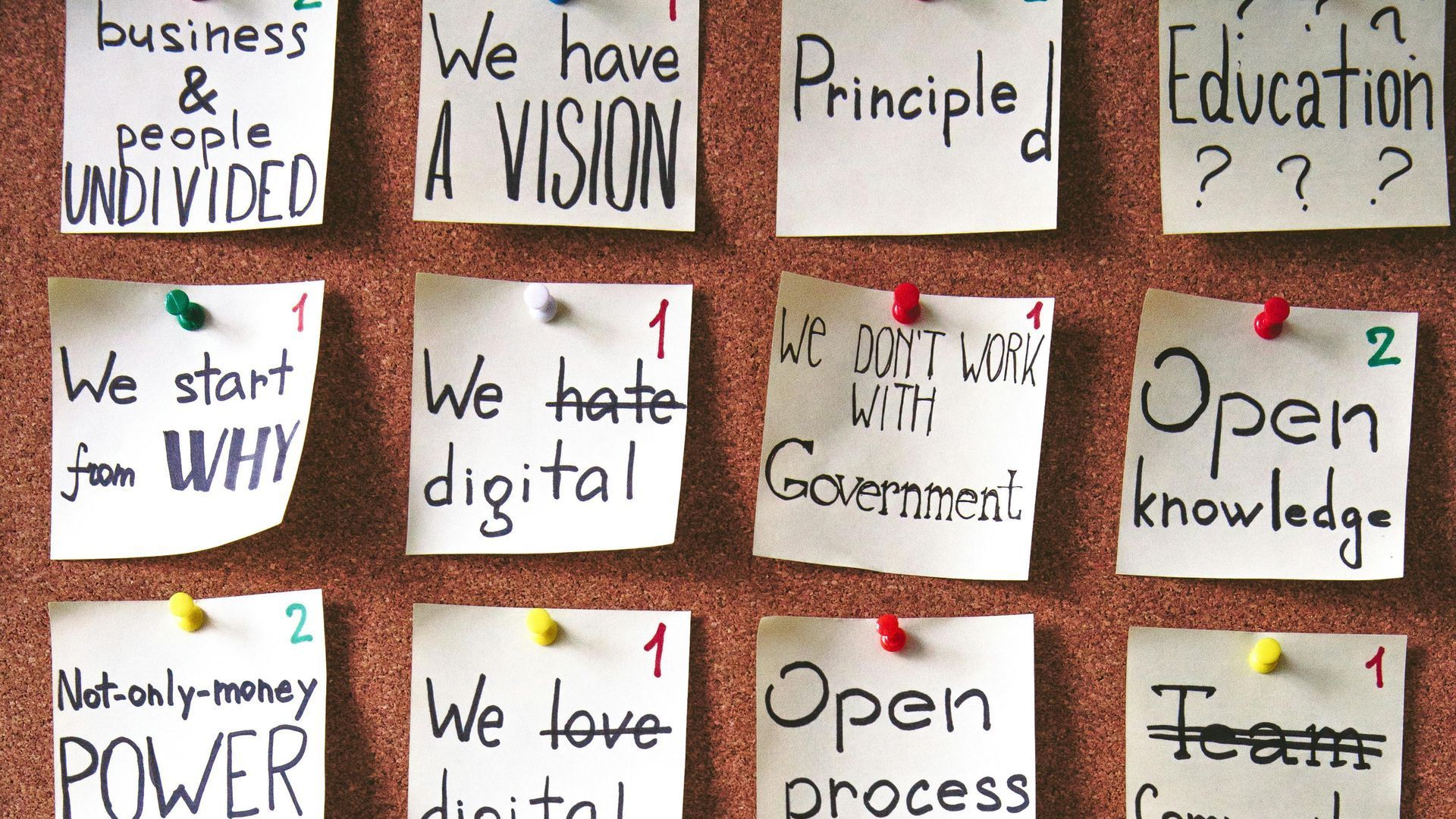 A bulletin board with sticky notes pinned to it including one that says