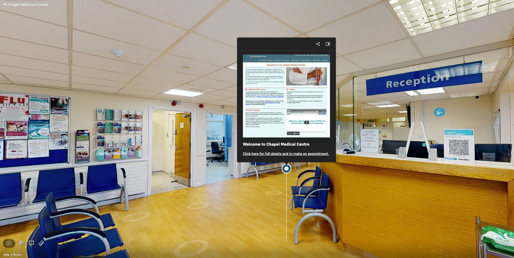 Bright hospital reception area with blue chairs, yellow floor, and a large digital information screen.