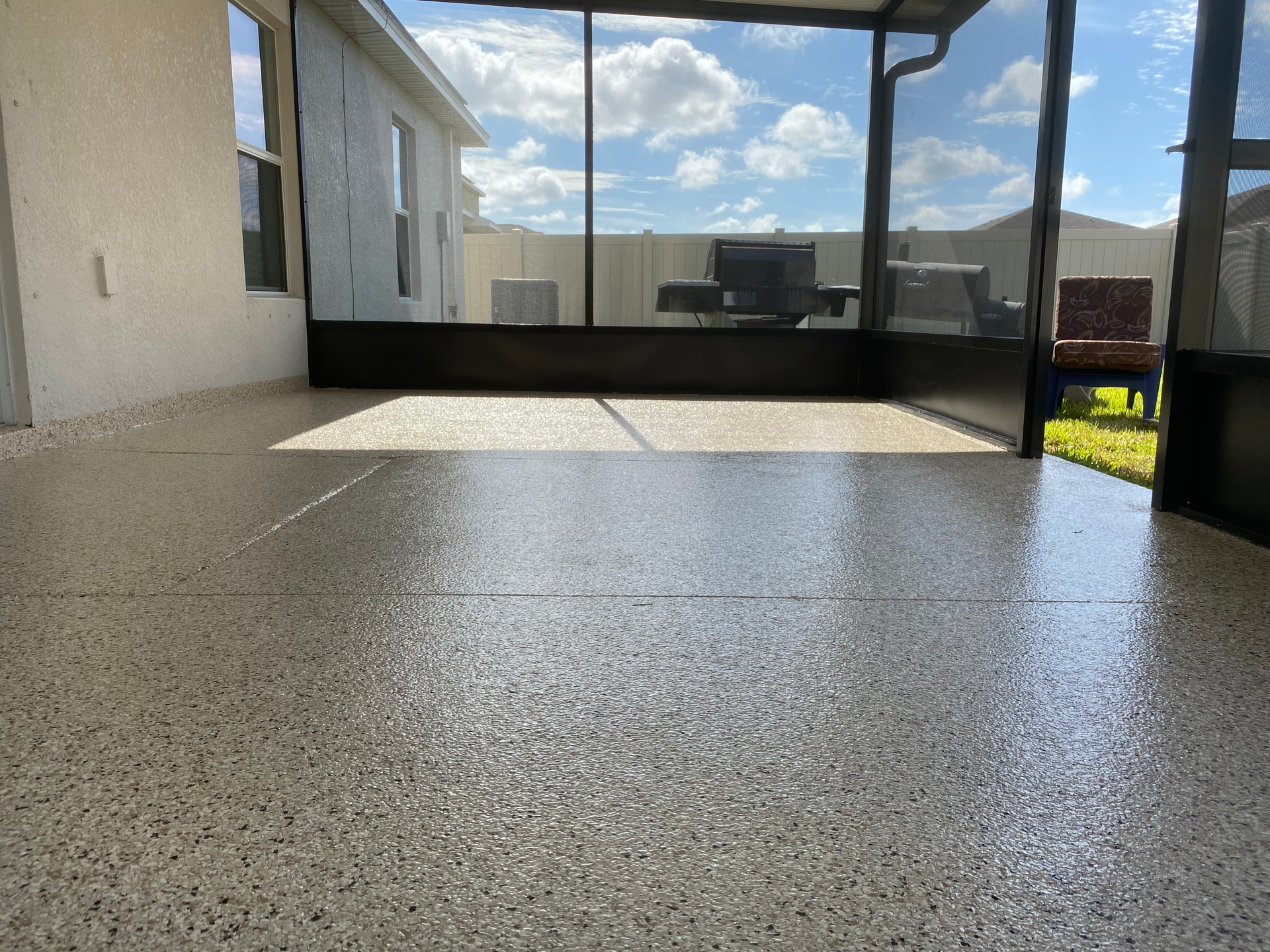 A patio with a screened in porch and a concrete floor.