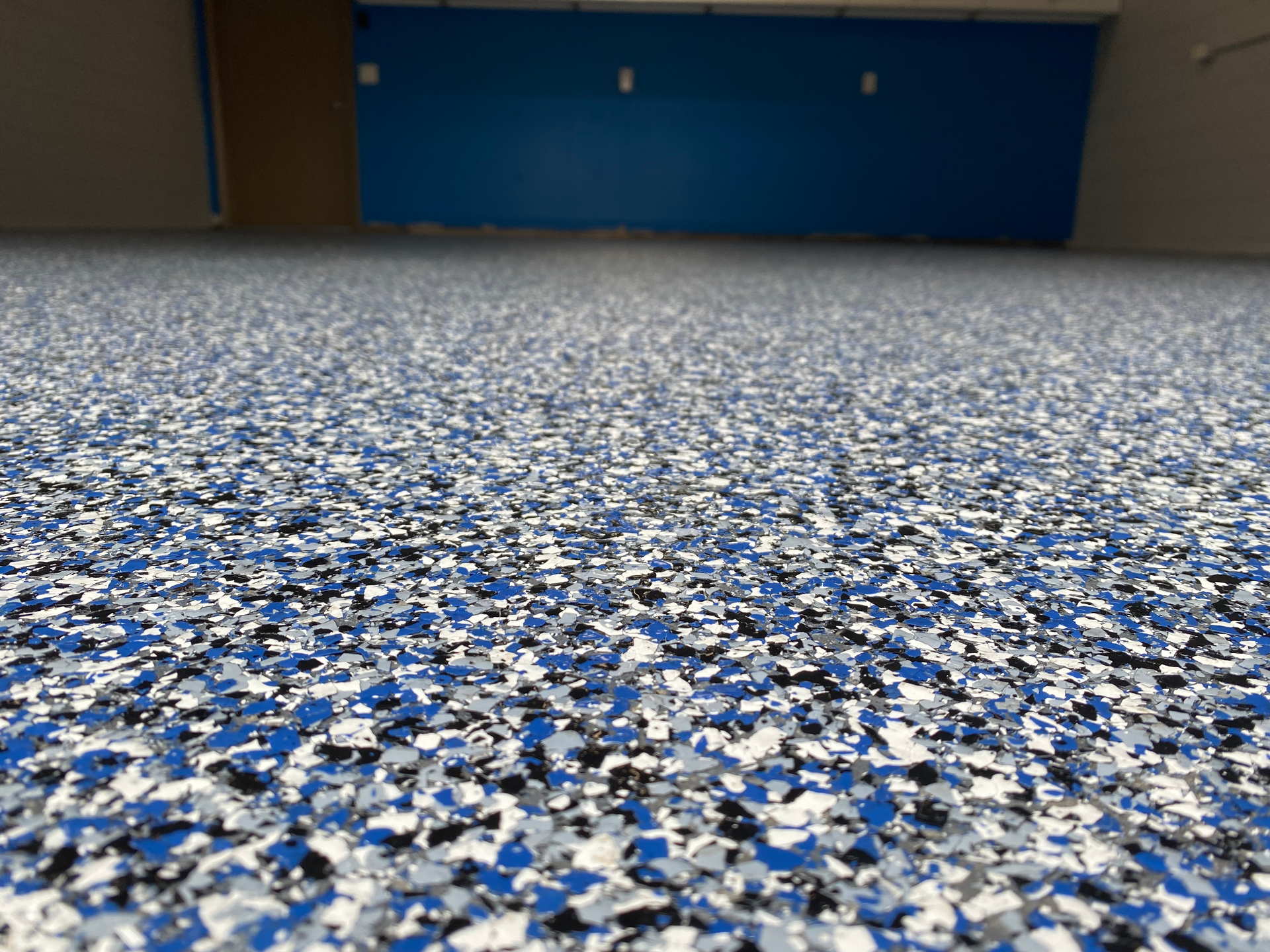 A close up of a blue , white and black floor in a garage.