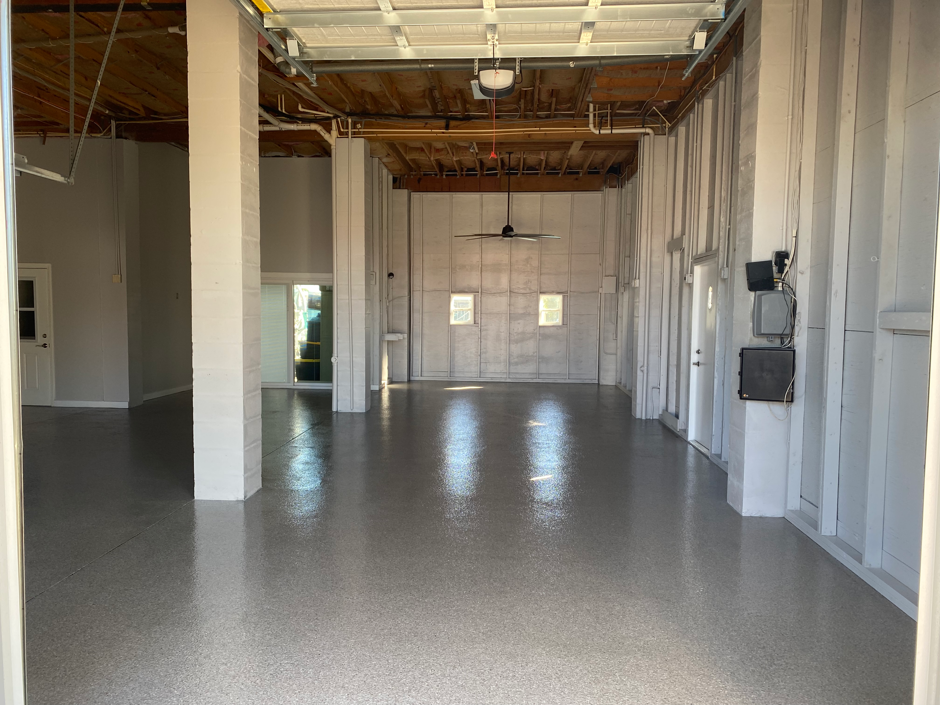 An empty garage with a garage door open and a ceiling fan