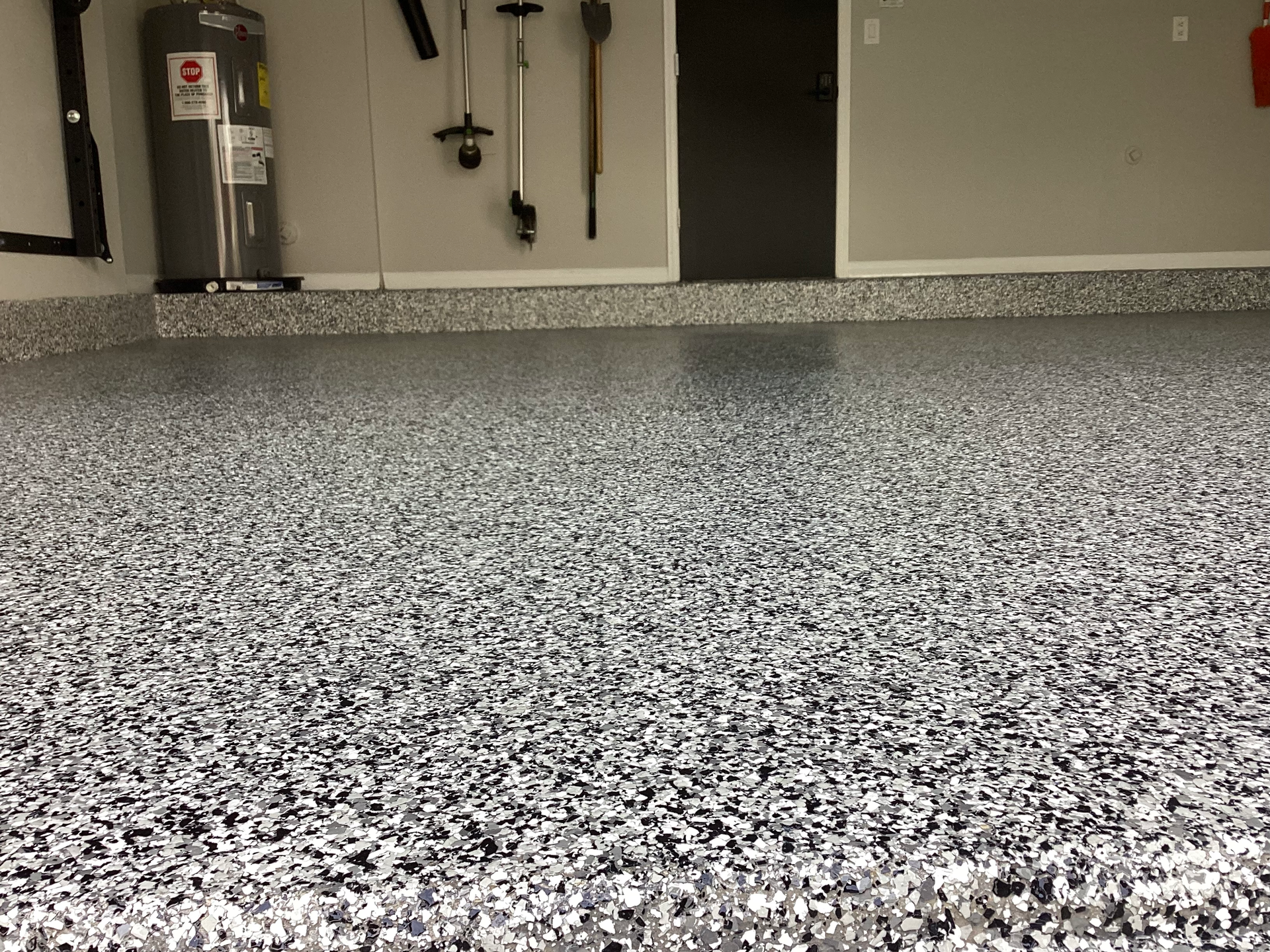 A close up of a garage floor with a water heater in the background.