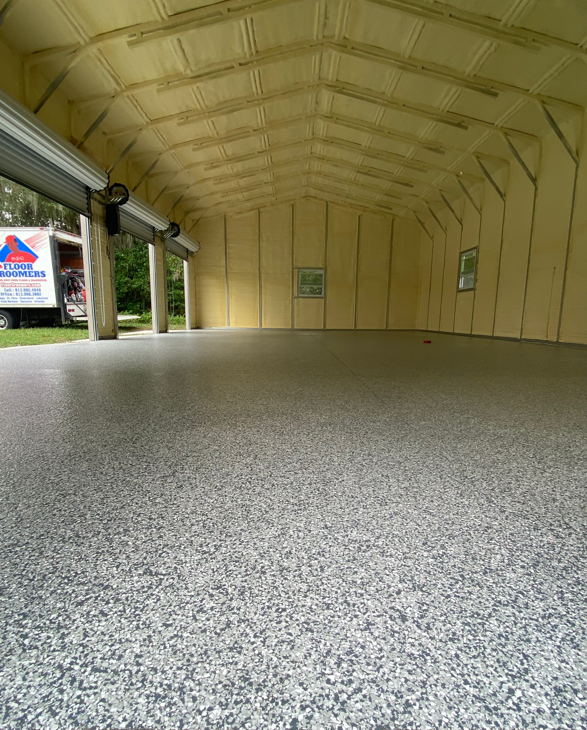 A large empty garage with a truck parked in the background.