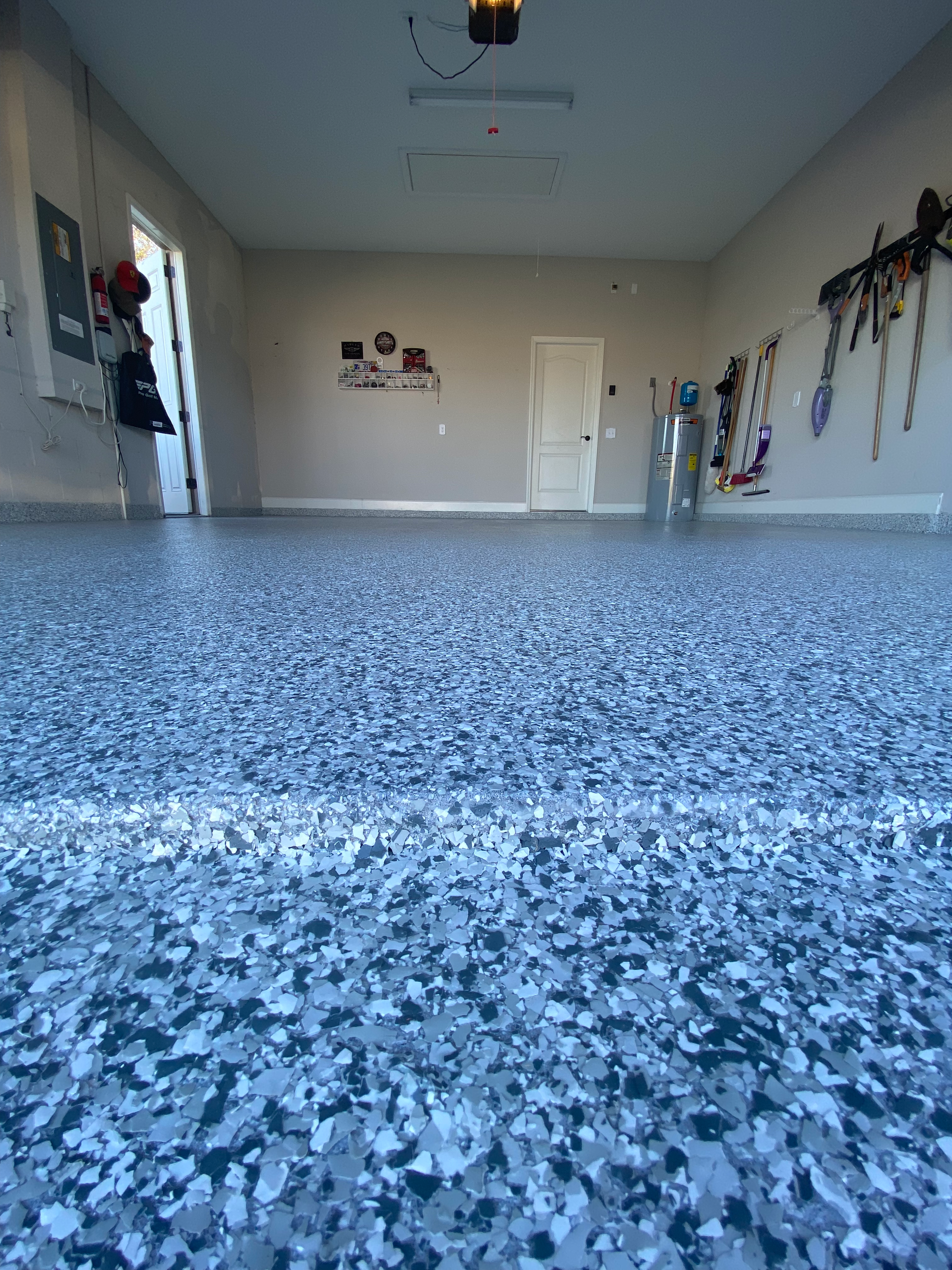 A garage with a gray and black floor and a ceiling fan.