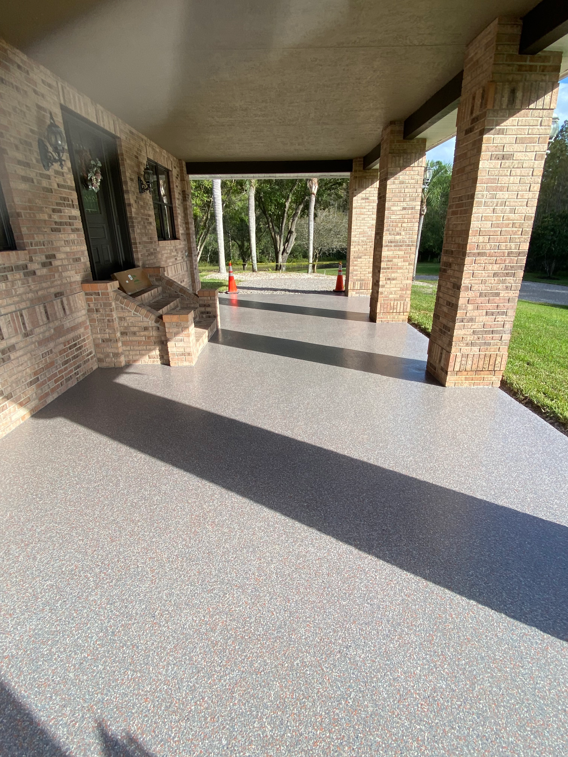 A porch with a concrete floor and a brick wall.