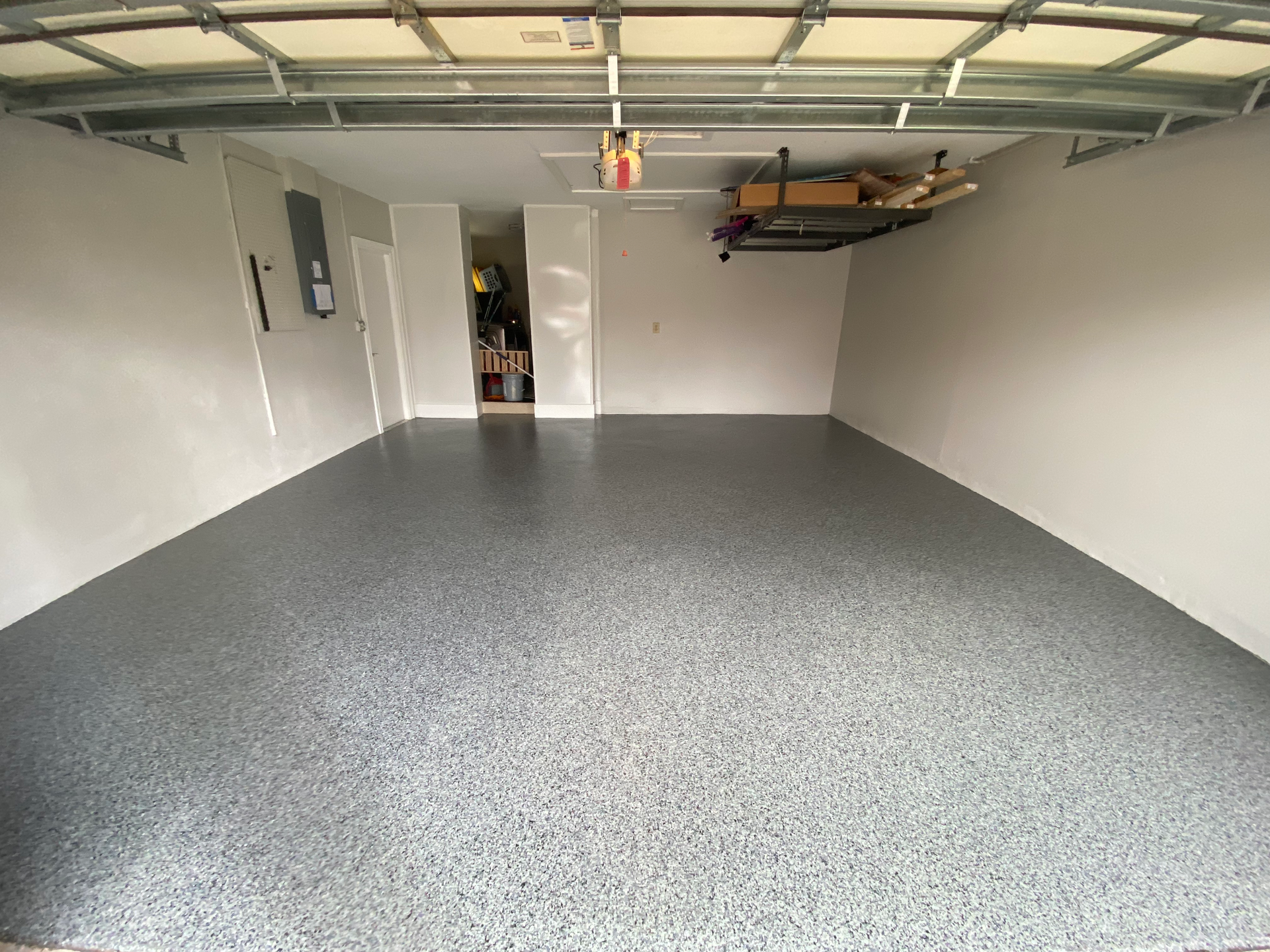 A garage with a gray floor and a white wall.