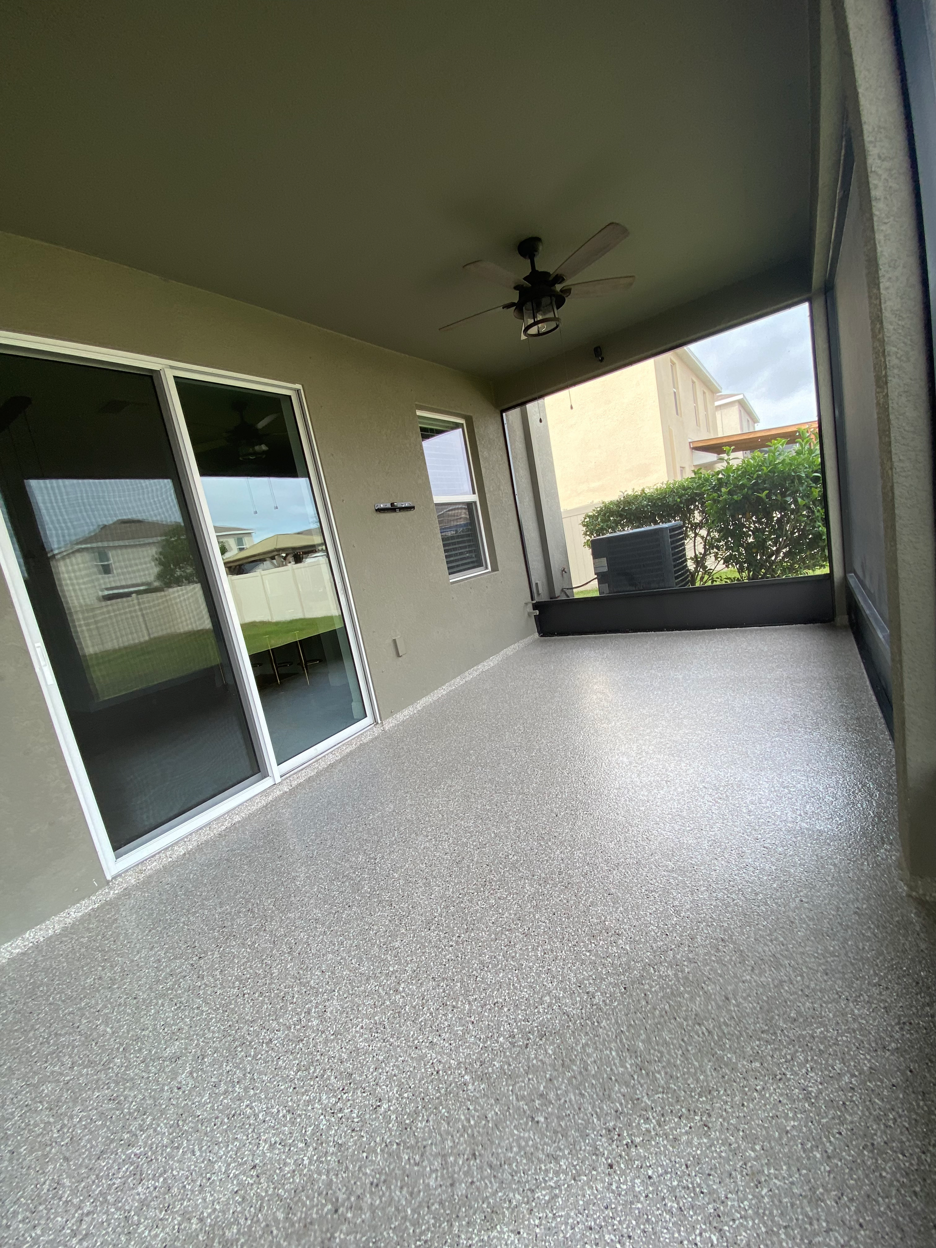 A patio with a ceiling fan and sliding glass doors.