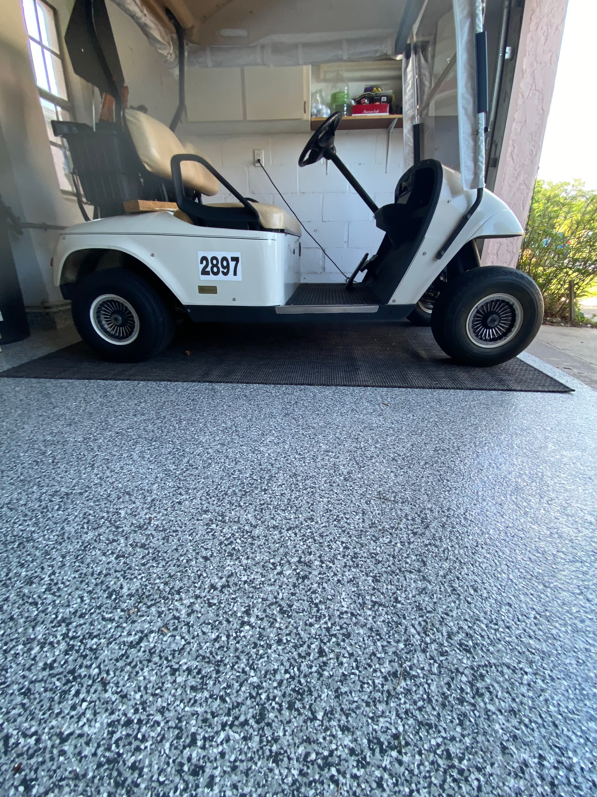 A white golf cart is parked in a garage.