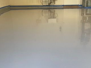 A garage floor with a reflection of a chair in it.