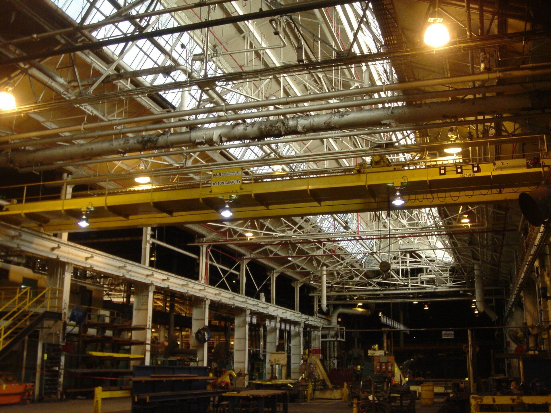 A large warehouse with a lot of pipes hanging from the ceiling