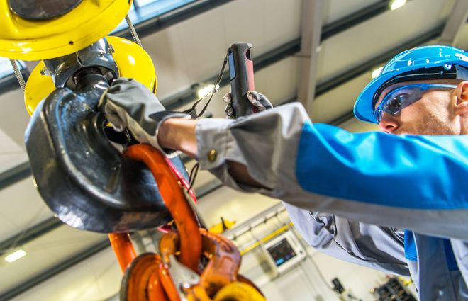 A man is working on a crane in a factory.