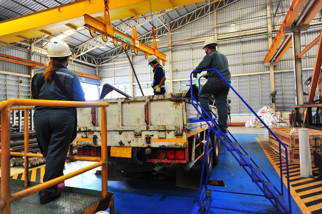 A group of people are working on a truck in a warehouse.