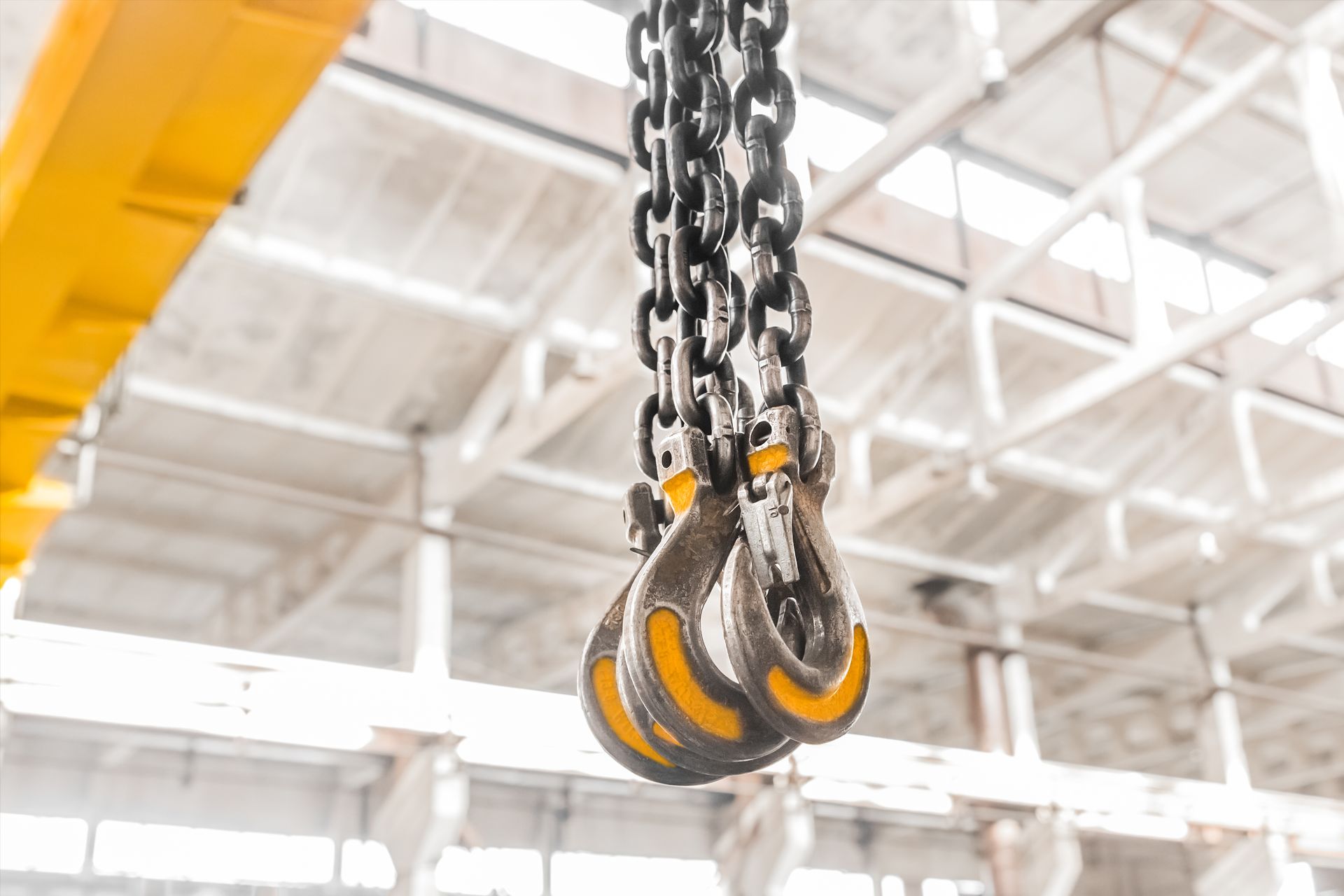 A close up of a chain with hooks hanging from the ceiling of a building.