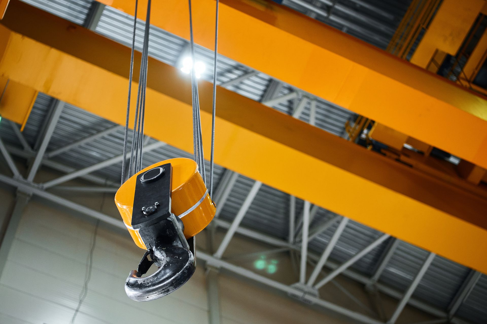 A crane hook is hanging from the ceiling of a building.