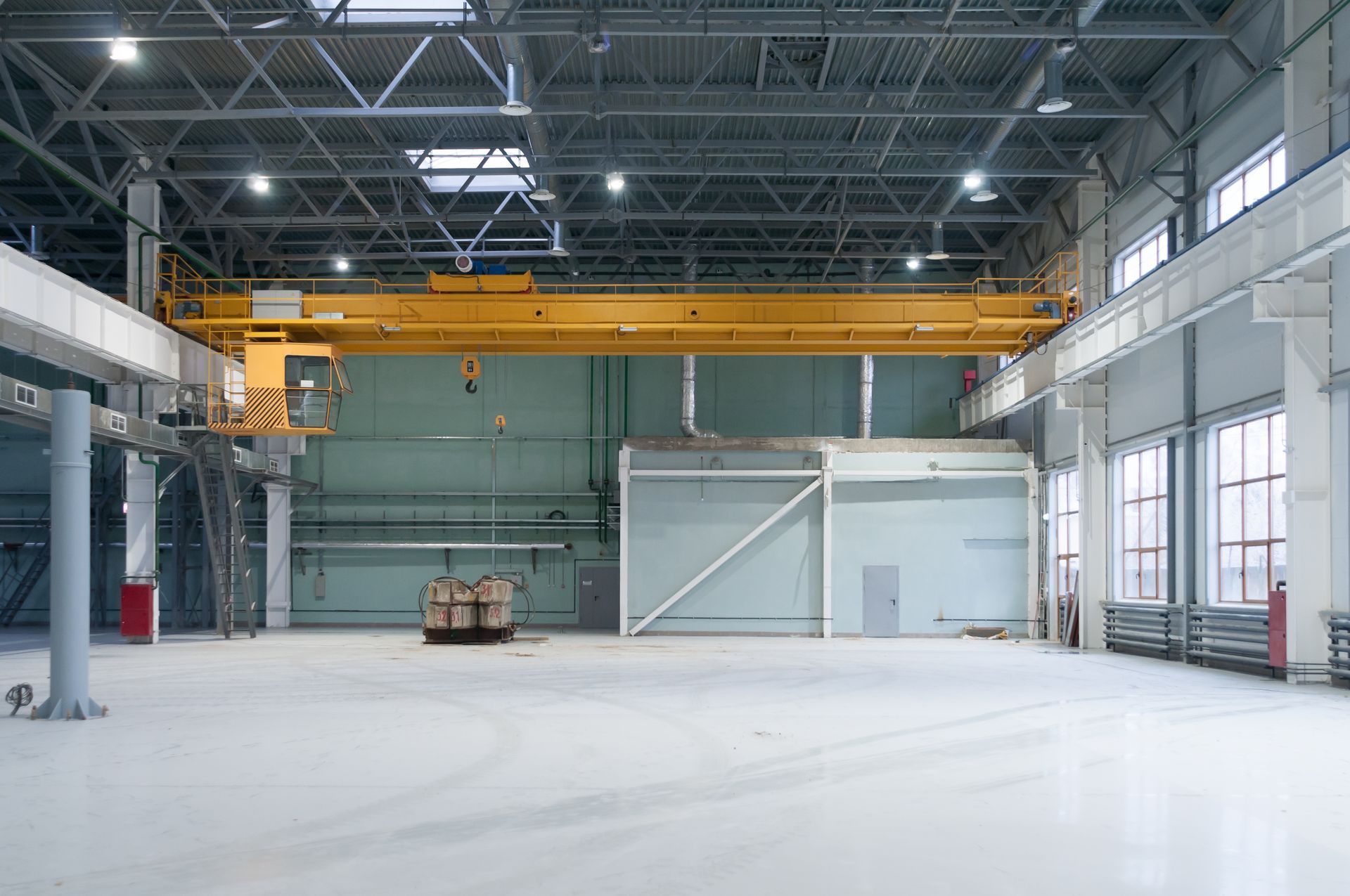 A large empty warehouse with a crane in the middle of it.