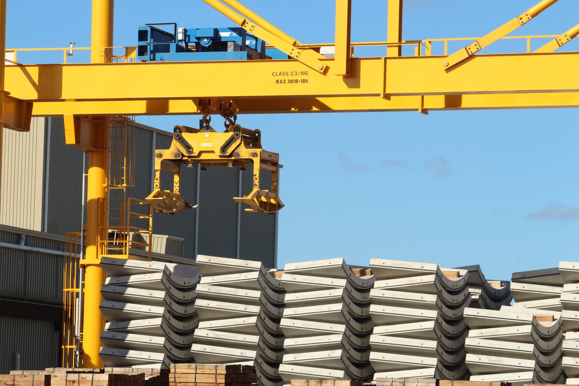 A yellow crane is lifting a stack of concrete blocks