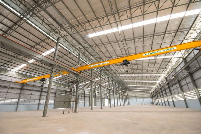A large empty warehouse with a crane hanging from the ceiling.