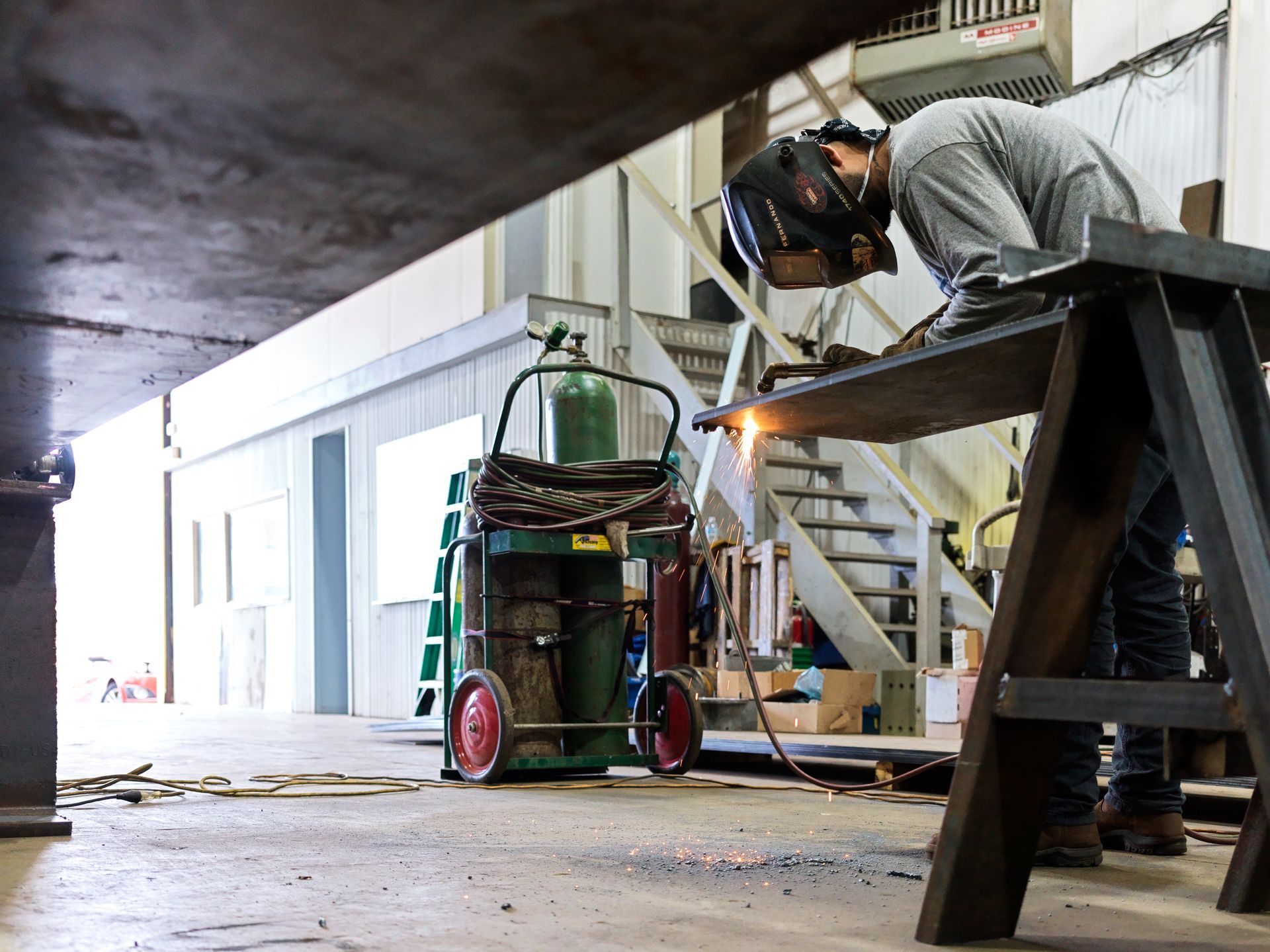 A man is welding a piece of metal in a factory.
