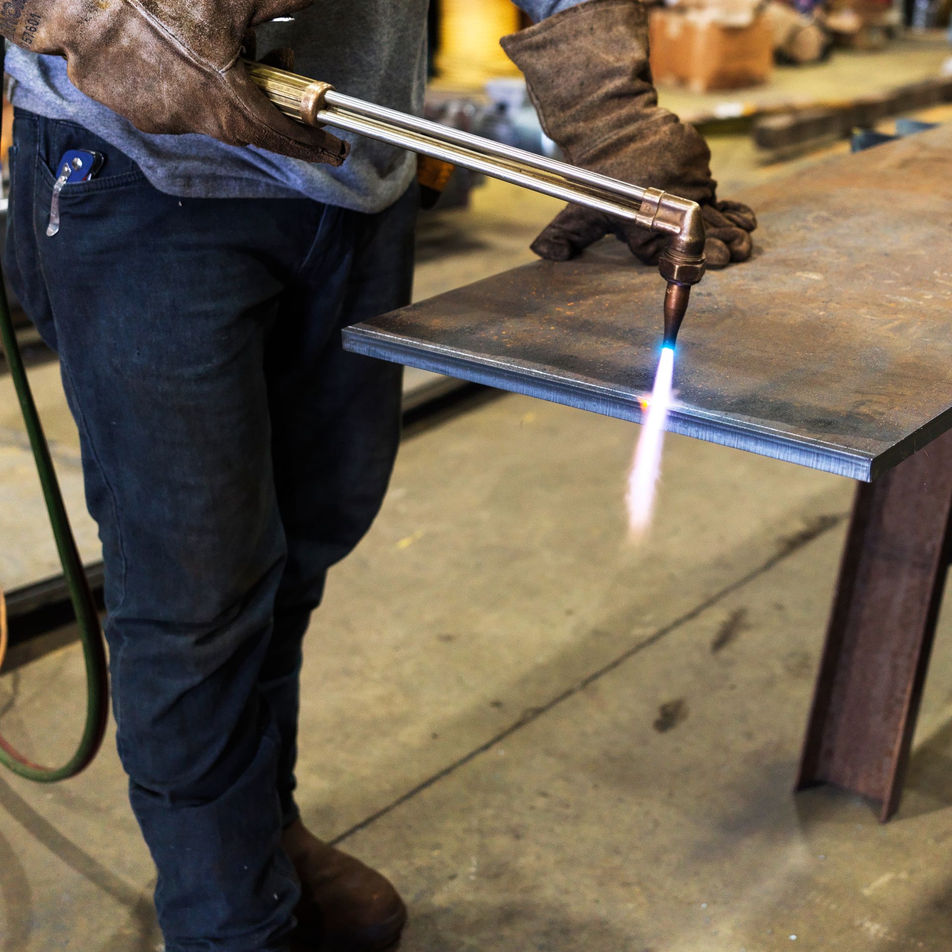A man is cutting a piece of metal with a torch