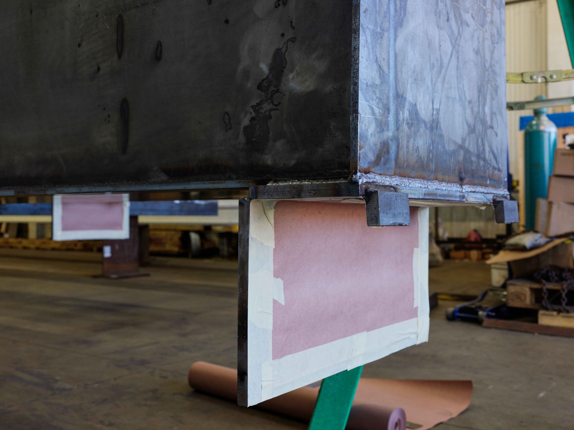 A large piece of metal is sitting on a green stand in a factory.