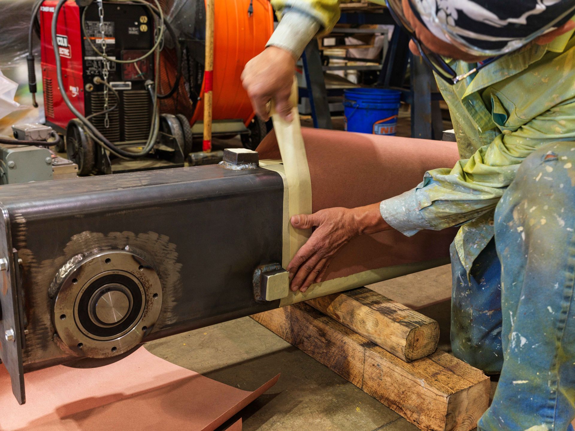 A man wearing a helmet is working on a piece of metal