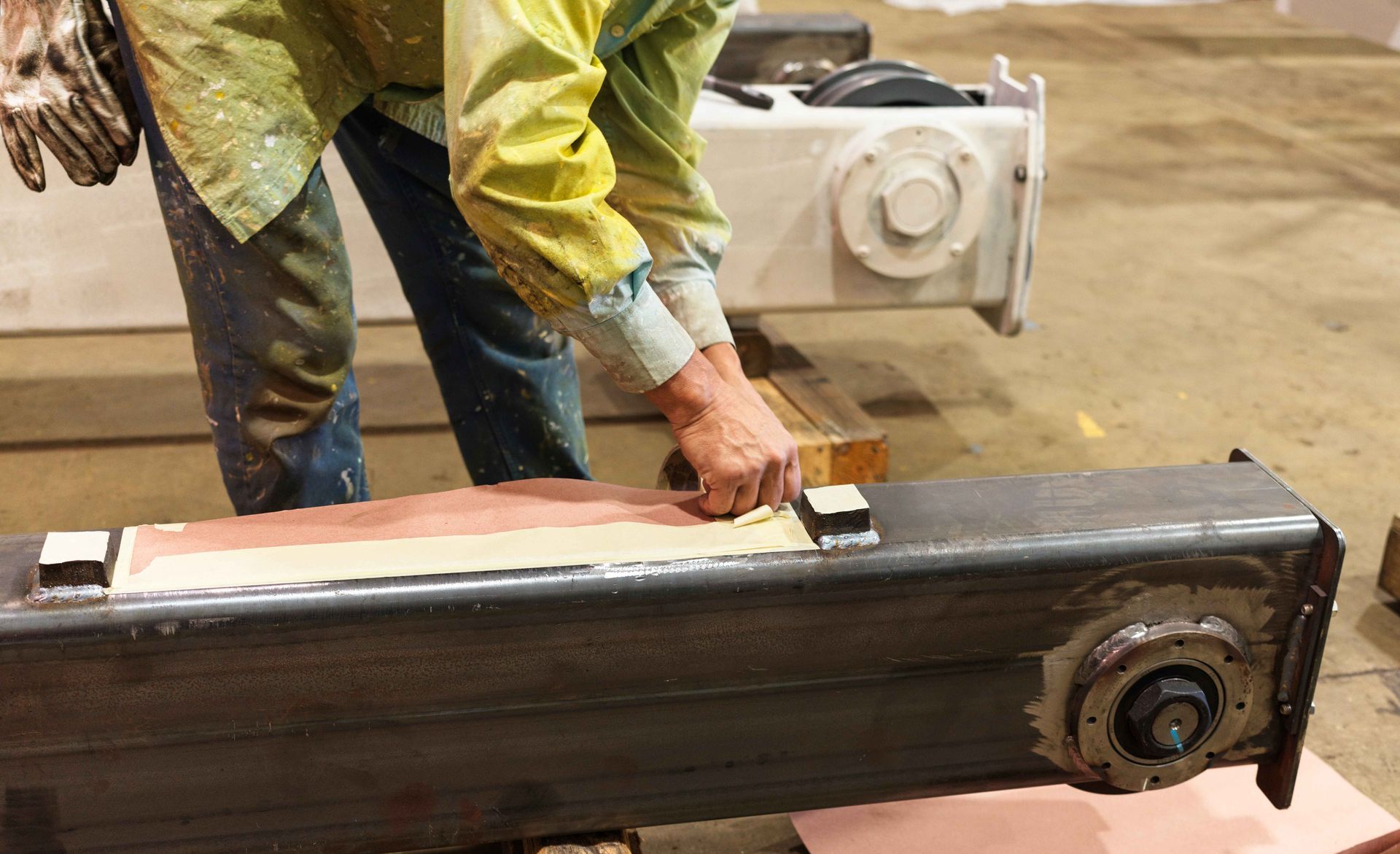 A man is working on a piece of metal in a factory.