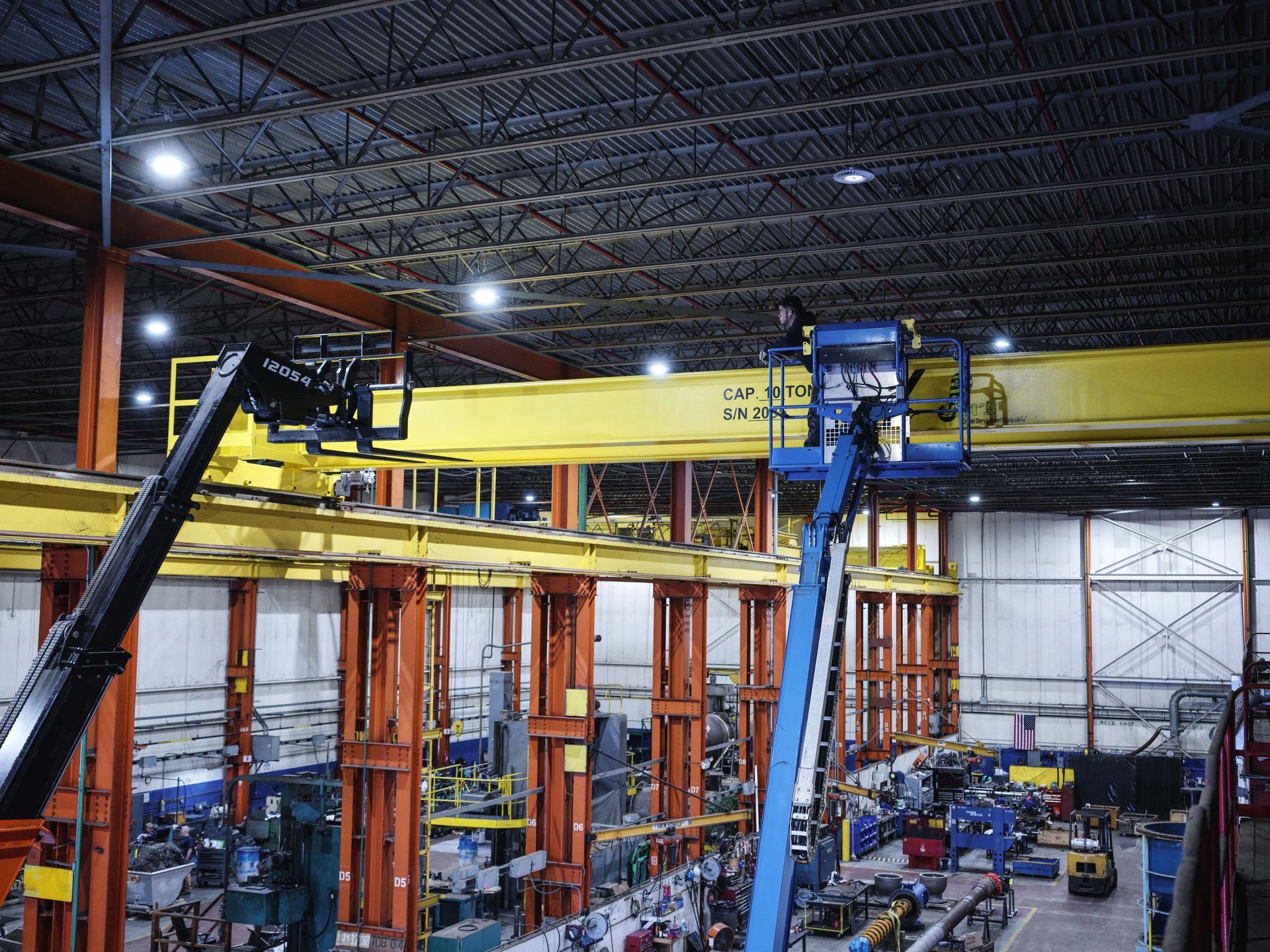 A man is working on a crane in a factory.