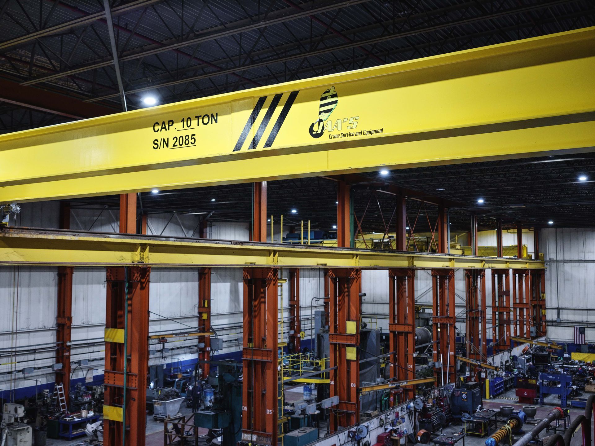A large yellow crane is hanging from the ceiling of a factory.