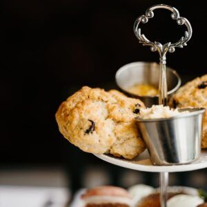 Tiered serving stand with scones, jam, and cream on a dark background