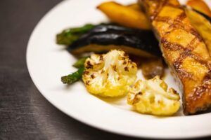 Grilled salmon with roasted vegetables on a white plate